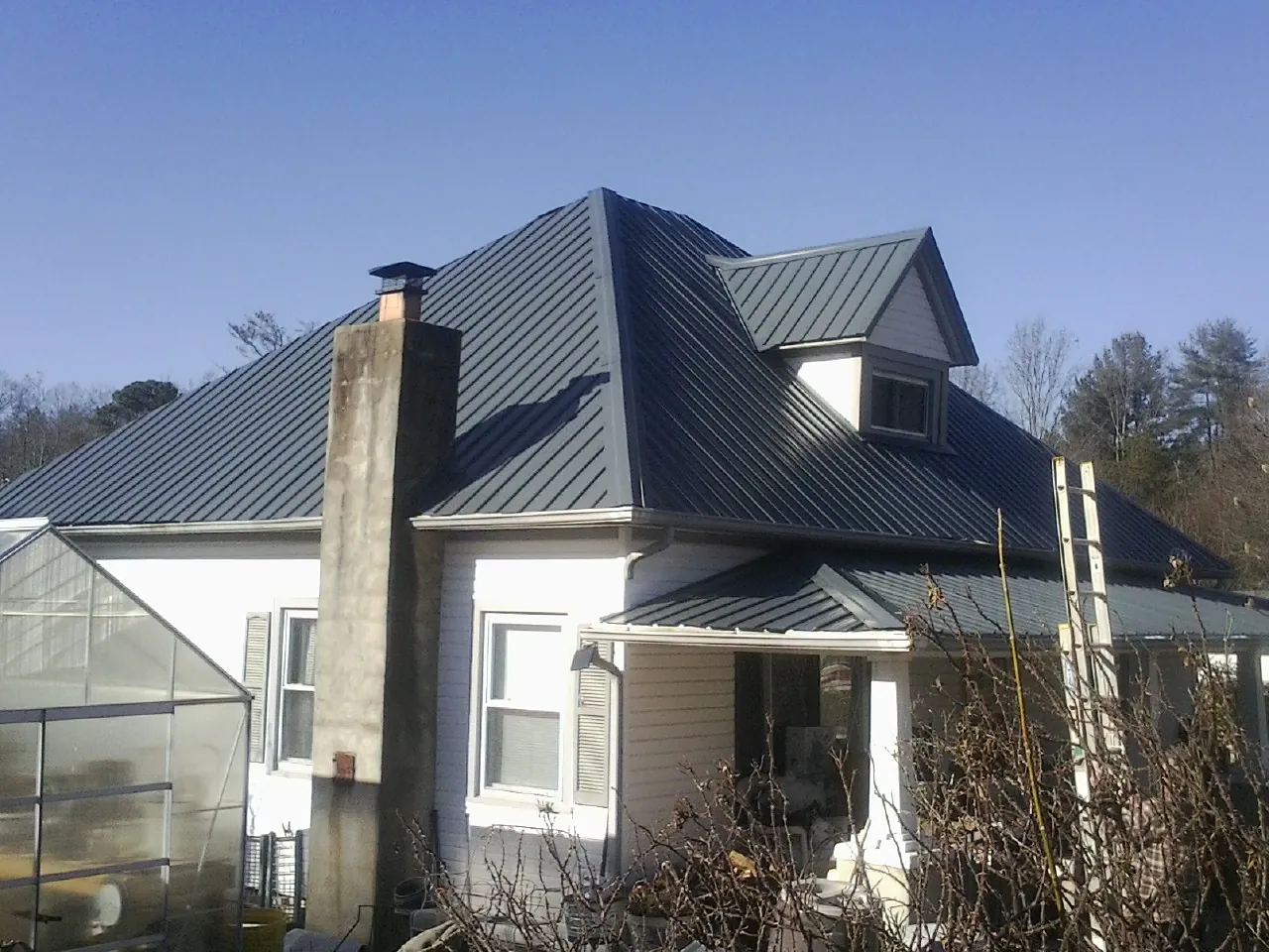 Dark blue standing seam metal roof on a white farmhouse with dormer — Slate & Tile Roof Repair by Roofing Brothers in Connoquenessing