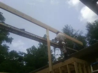 Carpenter setting a ridge beam over a new addition frame — Ice Dam Removal by Roofing Brothers in Connoquenessing
