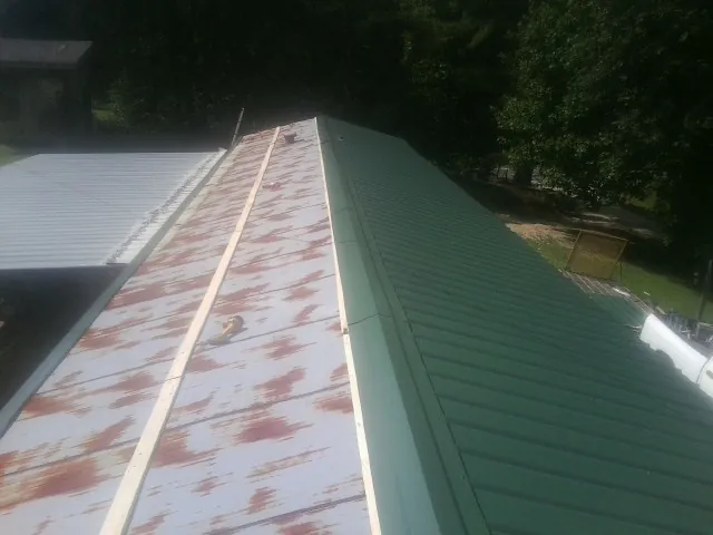 Old rusted panels beside newly installed green metal roofing — Wind Damage Roof Repair by Roofing Brothers in Connoquenessing
