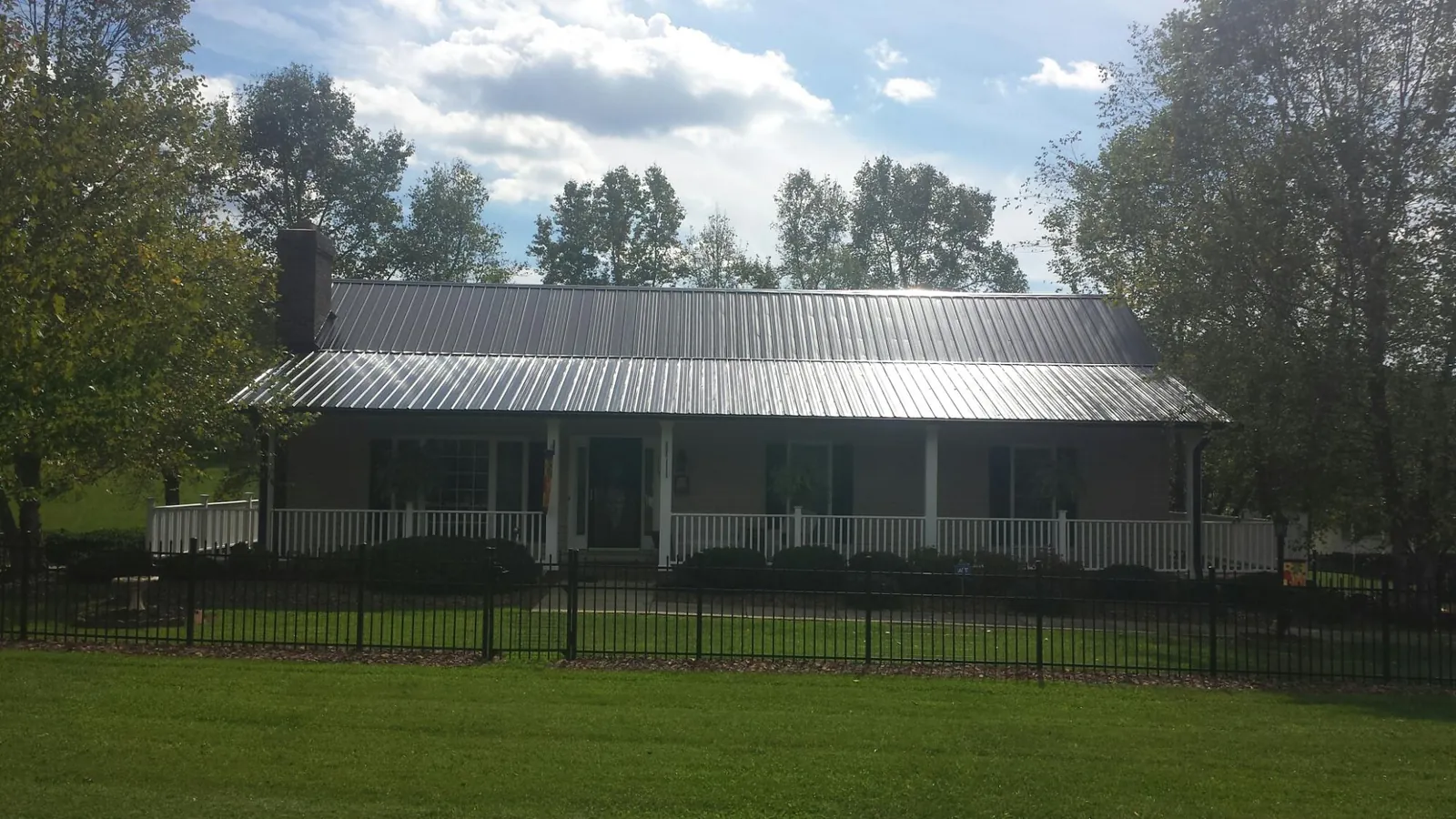 Gray metal roof on a brick ranch with a full width front porch — Gutter Guard Installation work by our crew in Connoquenessing