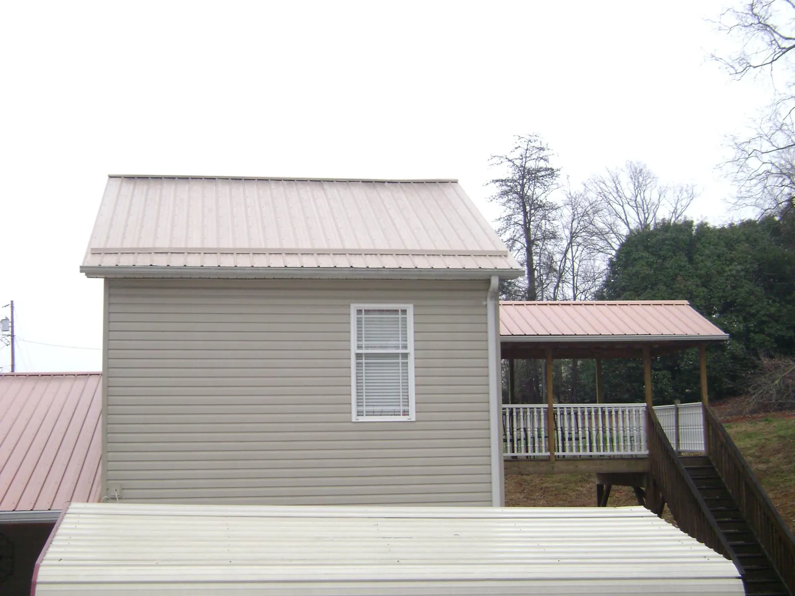 Tan metal roofs on a two story addition and attached porch, from a Roof Replacement job in Connoquenessing