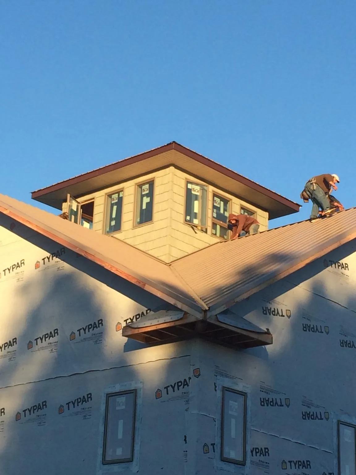 Roofers working around a rooftop cupola on a new metal roof at sunset — Roof Waterproofing in Connoquenessing by Roofing Brothers